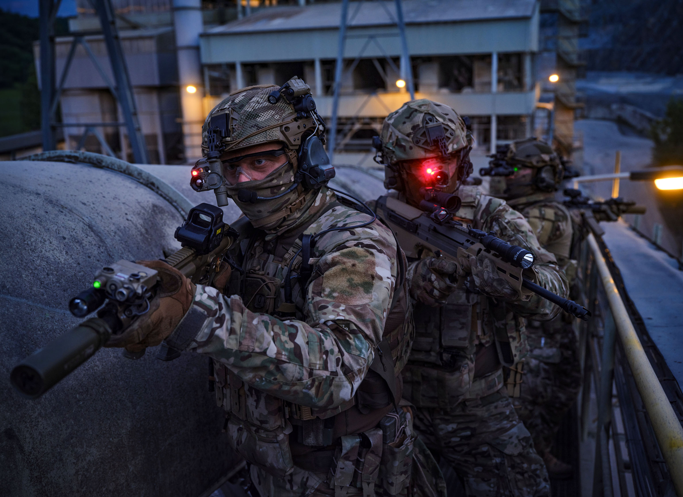 Mehrere Soldaten bewegen sich bei Dämmerung auf einem industriellen Gebäude. An deren Helmen sind TILOs befestigt um den weg zu beleuchten.